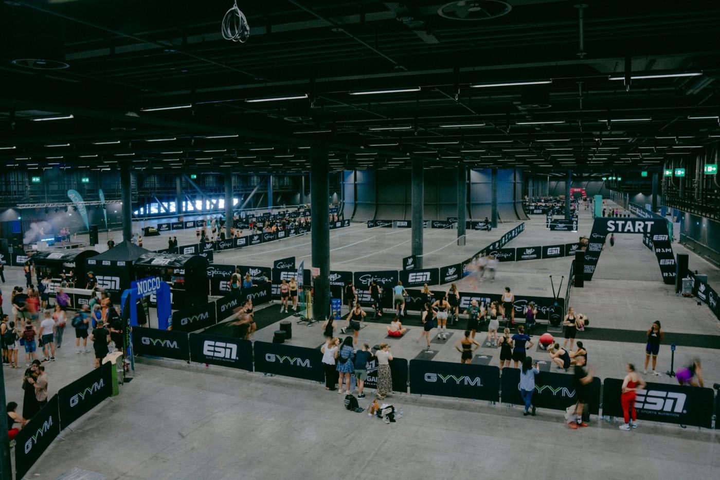 Blick über die HYBRID GAMES Arena mit gebrandeten Banden, Wettkampfflächen und Publikum
