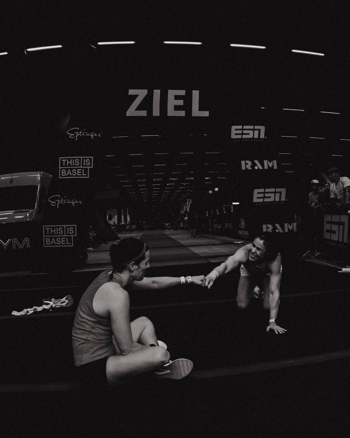 Athletin am Boden vor dem Zielbogen in einer Schwarzweissaufnahme